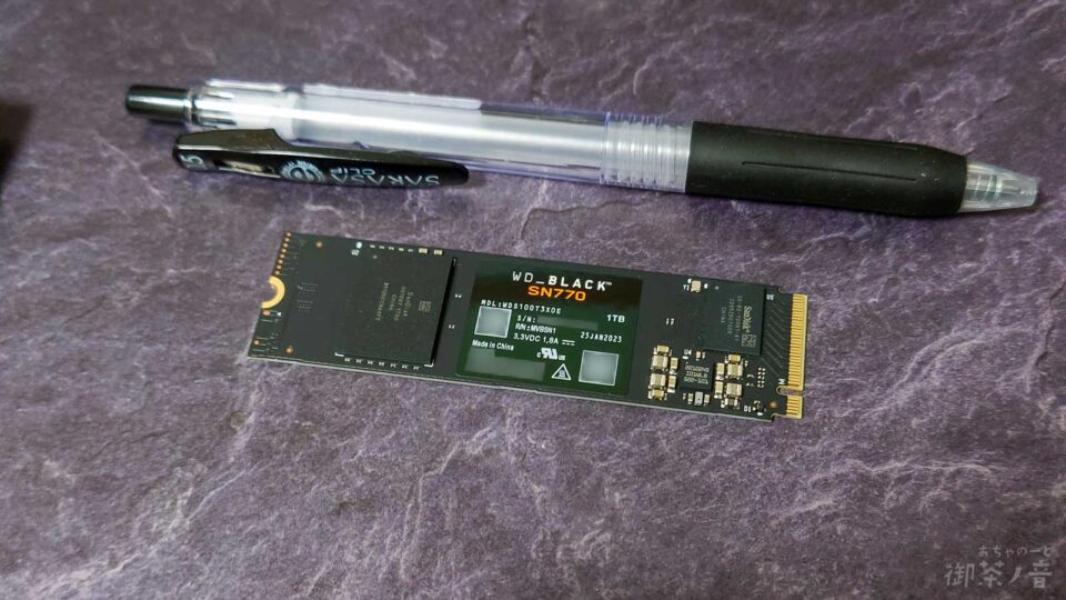 ボールペンとM.2 SSDの大きさ比較。ボールペンよりもSSDのほうが小さい。そして薄い。